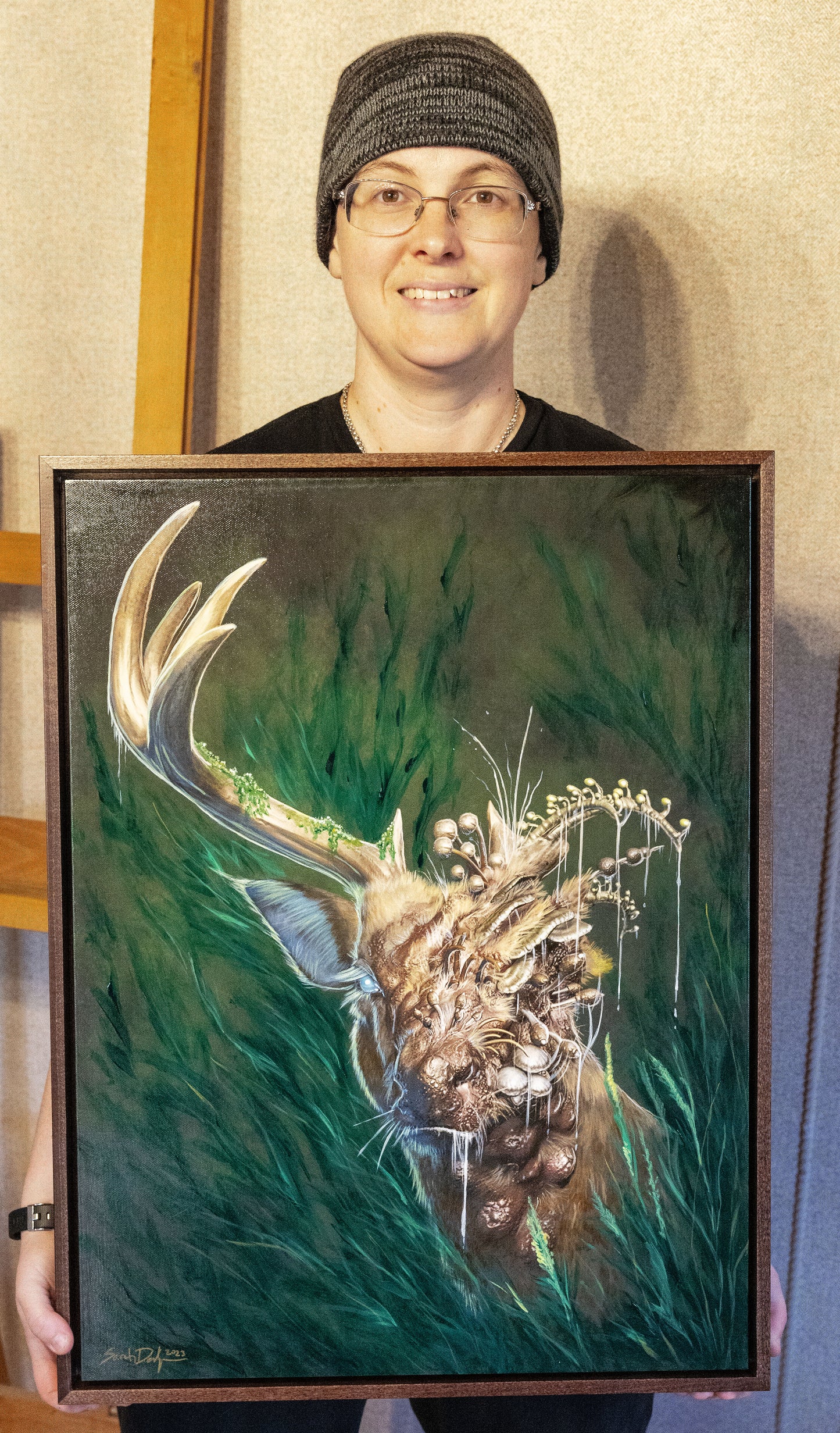 Sarah Dahlinger poses with the canvas. It is framed and has more detail than the print.